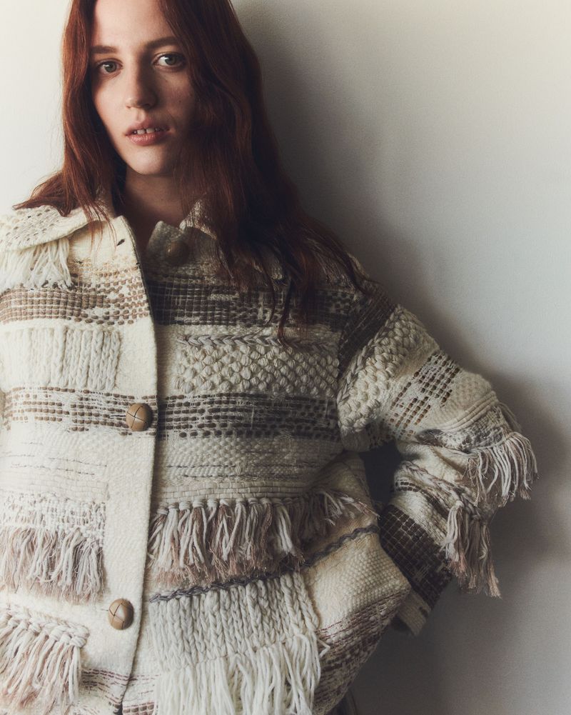 Model Julia Banas wearing a textured cream fringed jacket against a plain white background for Lafayette 148