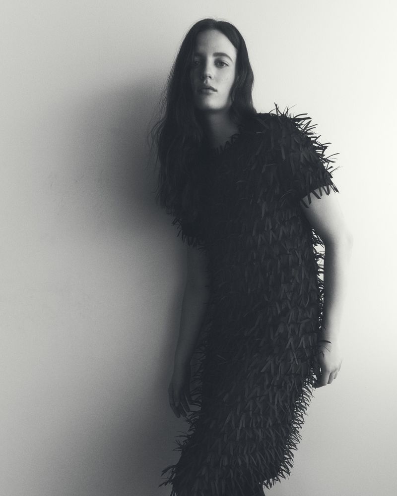 Model Julia Banas wearing a dark fringe dress against a neutral studio backdrop for Lafayette 148 Fall 2025.