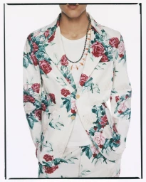 Model wearing a white floral print suit jacket and matching trousers over a white t-shirt against a plain backdrop.