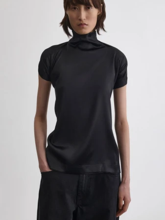 Model wearing a black turtleneck top and dark trousers against a plain white background for Phoebe Philo.