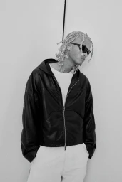 Model wearing black leather jacket and sunglasses standing against a plain white background for H&M.