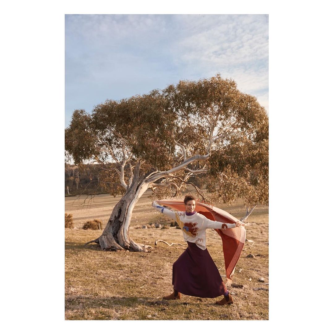Model standing outdoors near a eucalyptus tree holding a rust-colored scarf in an Australian landscape for Made with Love.