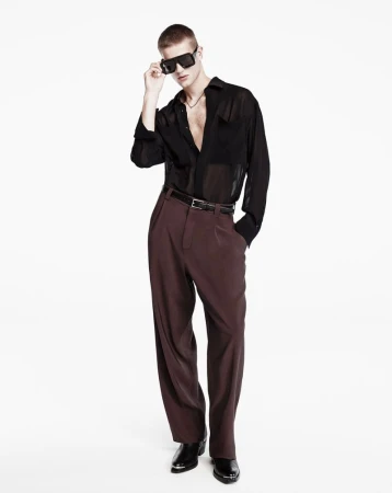 Male model wearing oversized black sheer shirt and dark trousers against a white background for Zara Man Evening.