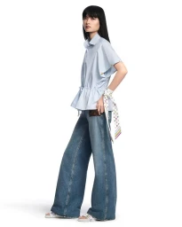 Model wearing a light blue button-down shirt and wide-leg denim jeans against a seamless white background.