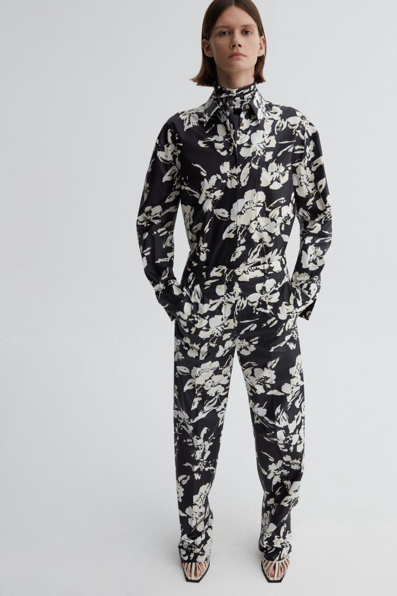 Model wearing a black and white floral print long-sleeve shirt and matching trousers against white