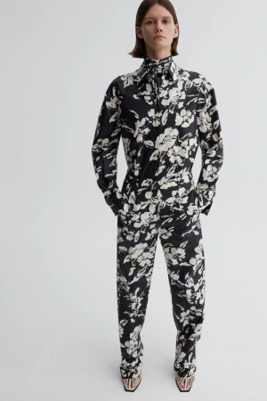 Model wearing a black and white floral print long-sleeve shirt and matching trousers against white