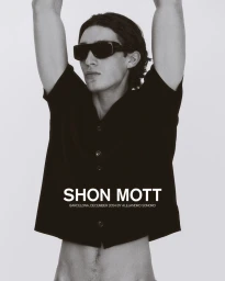 Model in black button-down shirt and sunglasses posing with arms raised against a plain background
