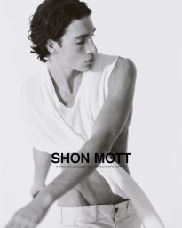 Model in white sleeveless top and light trousers posing against a bright background for Shon Mott SS25 campaign.