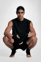 Male model wearing black athletic wear and hand wraps crouching against a bright white background for H&M Man Move SS25