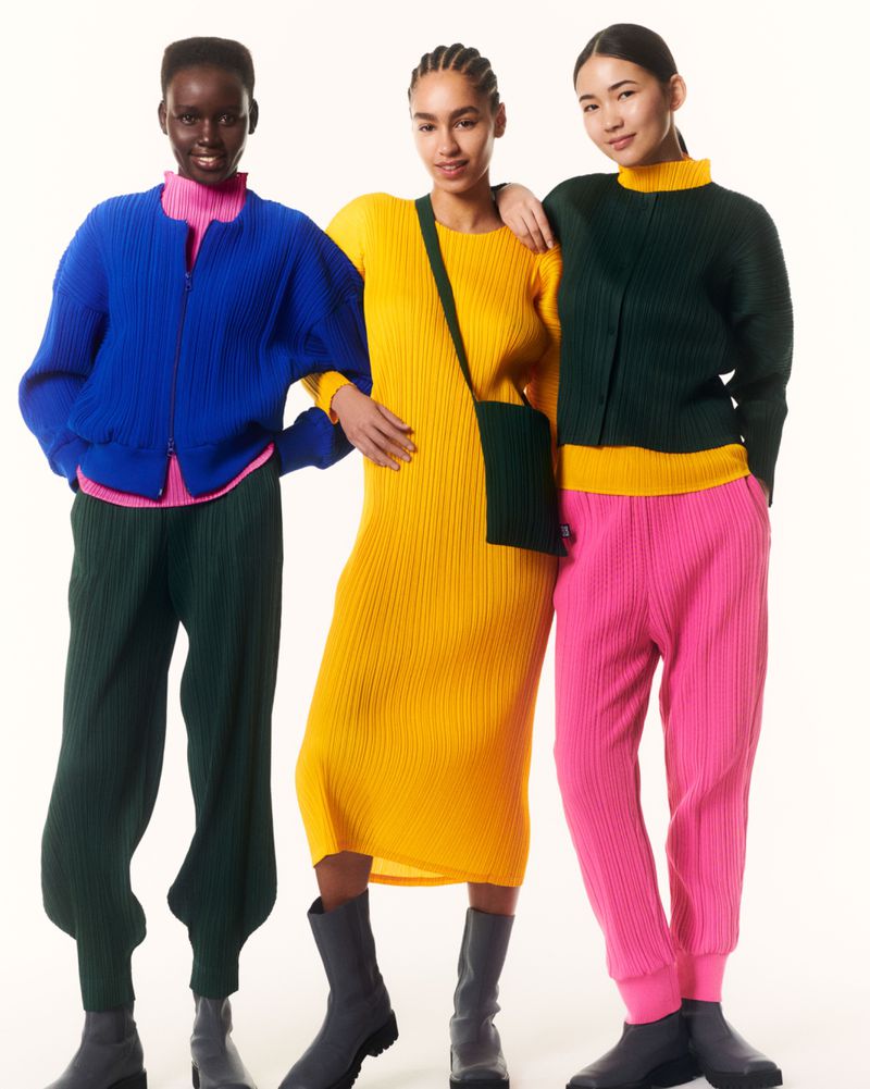 Three diverse fashion models showcase vibrant pleated knitwear: blue jacket, yellow dress, green jacket, all paired with ankle boots against a white backdrop.