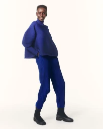 Model wearing a pleated blue top and matching blue trousers against a plain white background