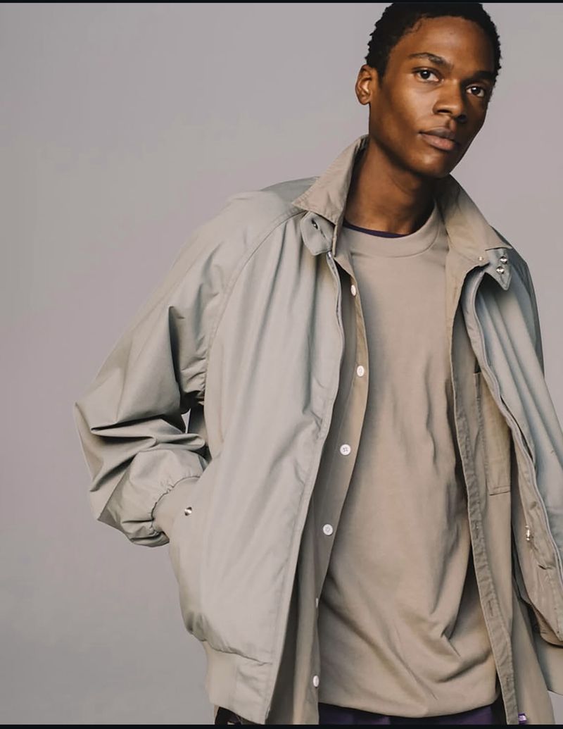 Model wearing a grey jacket over a matching t-shirt against a plain grey studio background for The North Face.