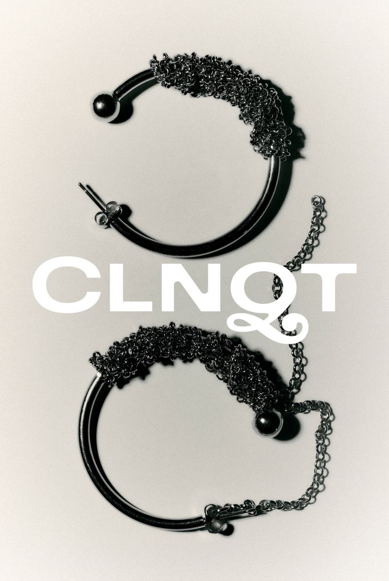 Close-up of two silver hoop earrings with intricate chain detail on a neutral background, showcasing elegant fashion jewelry.