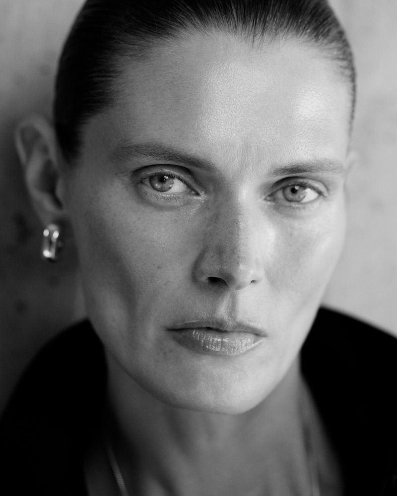 Close-up black and white portrait of a woman with slicked-back hair and silver earrings for COS Pre-Spring 2025.