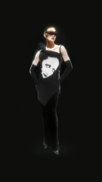 Model wearing a black dress with a face graphic, dark sunglasses, and black opera gloves against a black background