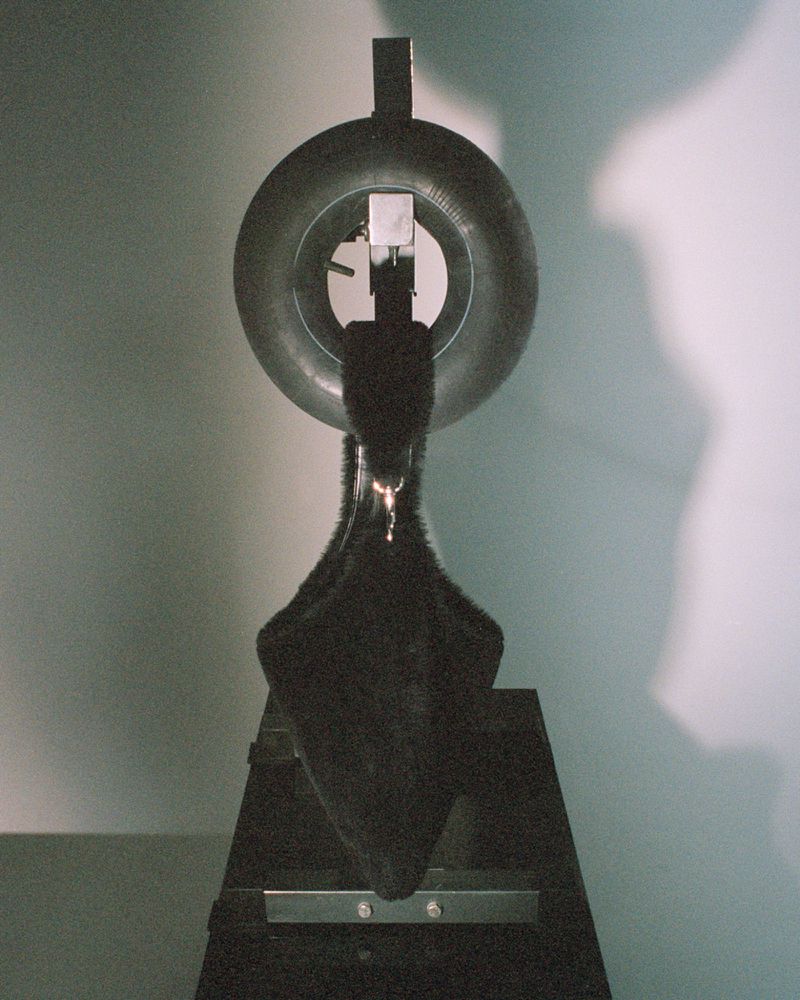 Black metal sculpture featuring a circular ring on a gray background in a studio setting with a focus on form and texture.