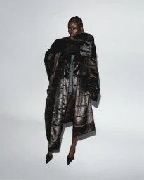 Model wearing a voluminous dark textured coat against a plain white studio backdrop for Rotate FW24 collection