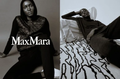 Black and white fashion portrait of a model wearing dark apparel and a hooded vest for Max Mara against a neutral studio background