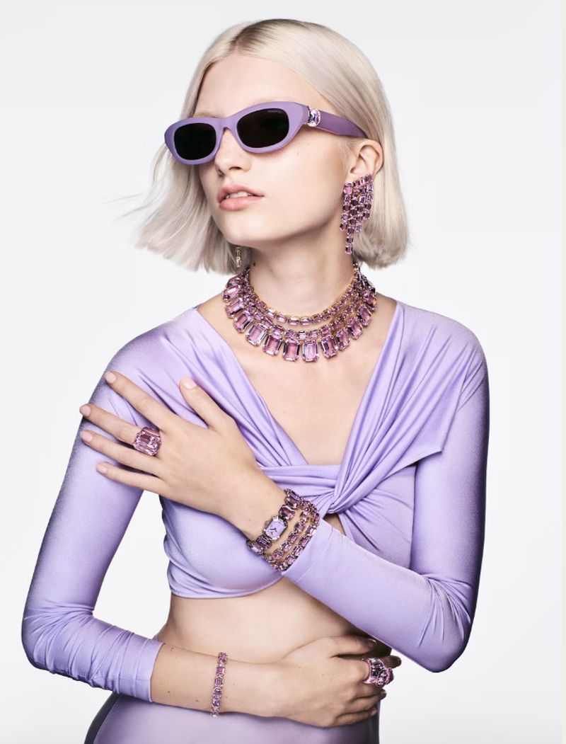 Fashionable woman in lilac outfit accessorized with statement jewelry: necklace, earrings, bracelets, rings and sunglasses.  