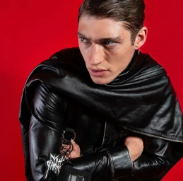 Model wearing black leather jacket and draped scarf with crimson red background