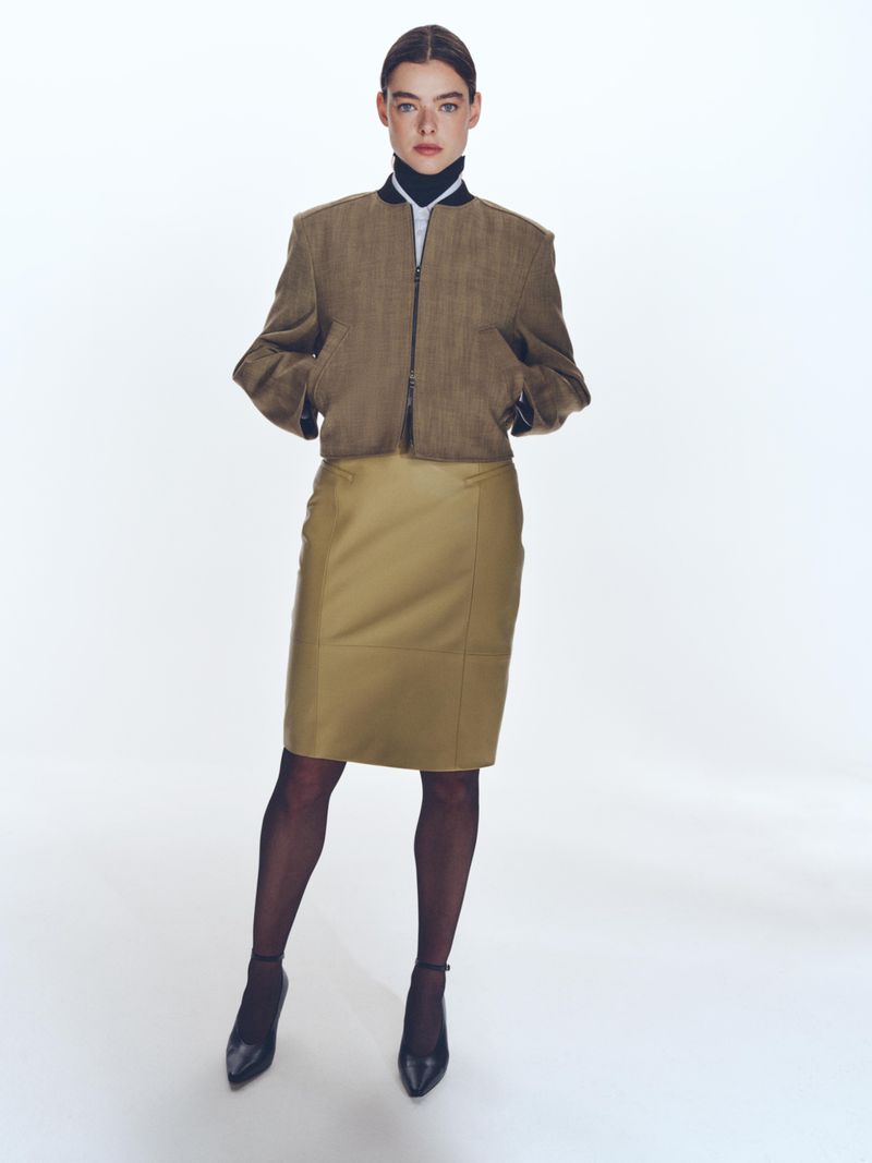 Model wearing a brown jacket and matching skirt with dark tights against a white background for BOSS Spring 2025 Womenswear