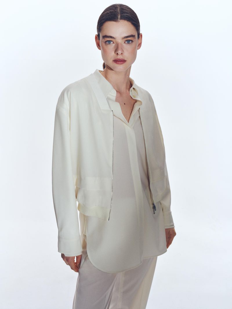 Model wearing a white shirt and jacket against a plain white studio background