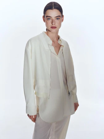 Model wearing a white shirt and jacket against a plain white studio background
