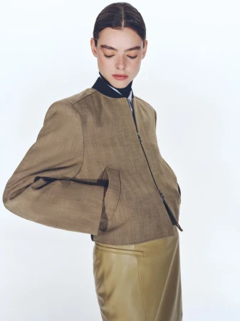 Model wearing a brown zip-up jacket and tan skirt against a clean white background for BOSS Spring 2025 womenswear