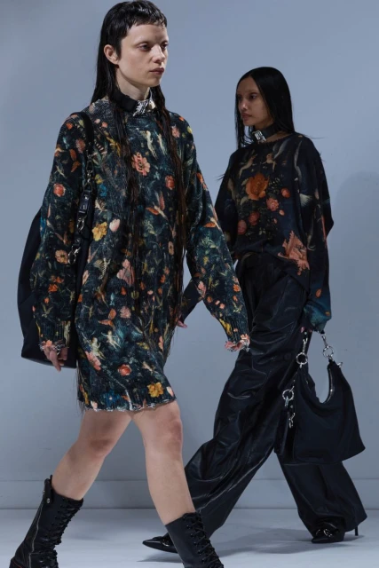 Two female fashion models showcase floral dresses and black boots in a studio, captured with a medium shot and soft lighting.