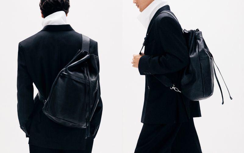 Two partial views of men wearing black blazers and backpacks against a bright white backdrop in a fashion or style setting.