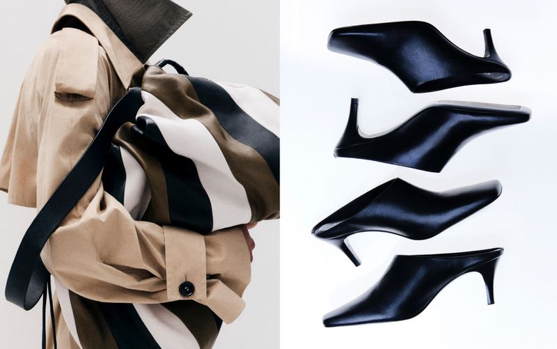 Tan trench coat, striped tote bag, and black heeled mules arranged on a white backdrop in a fashion-forward, studio product shot.