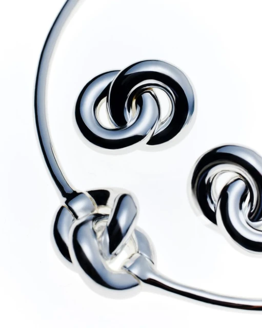 Silver choker necklace and matching earrings featuring a linked knot design, set against a clean white backdrop for jewelry product photography.