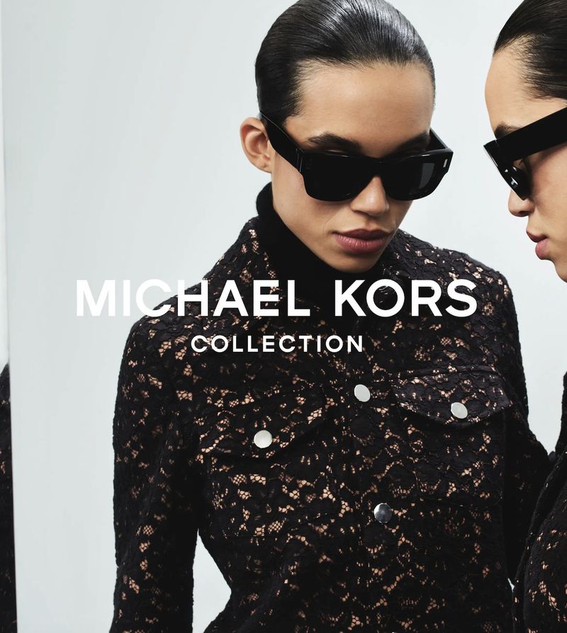 Fashion editorial image featuring two adult female models wearing black lace jackets and sunglasses, showcasing a Michael Kors collection.