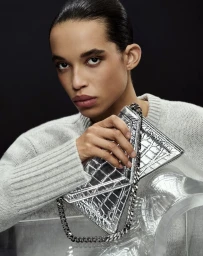 Model Lara Menezes holding a silver metallic handbag wearing a grey knit sweater in Michael Kors Collection SS 2025 campaign.