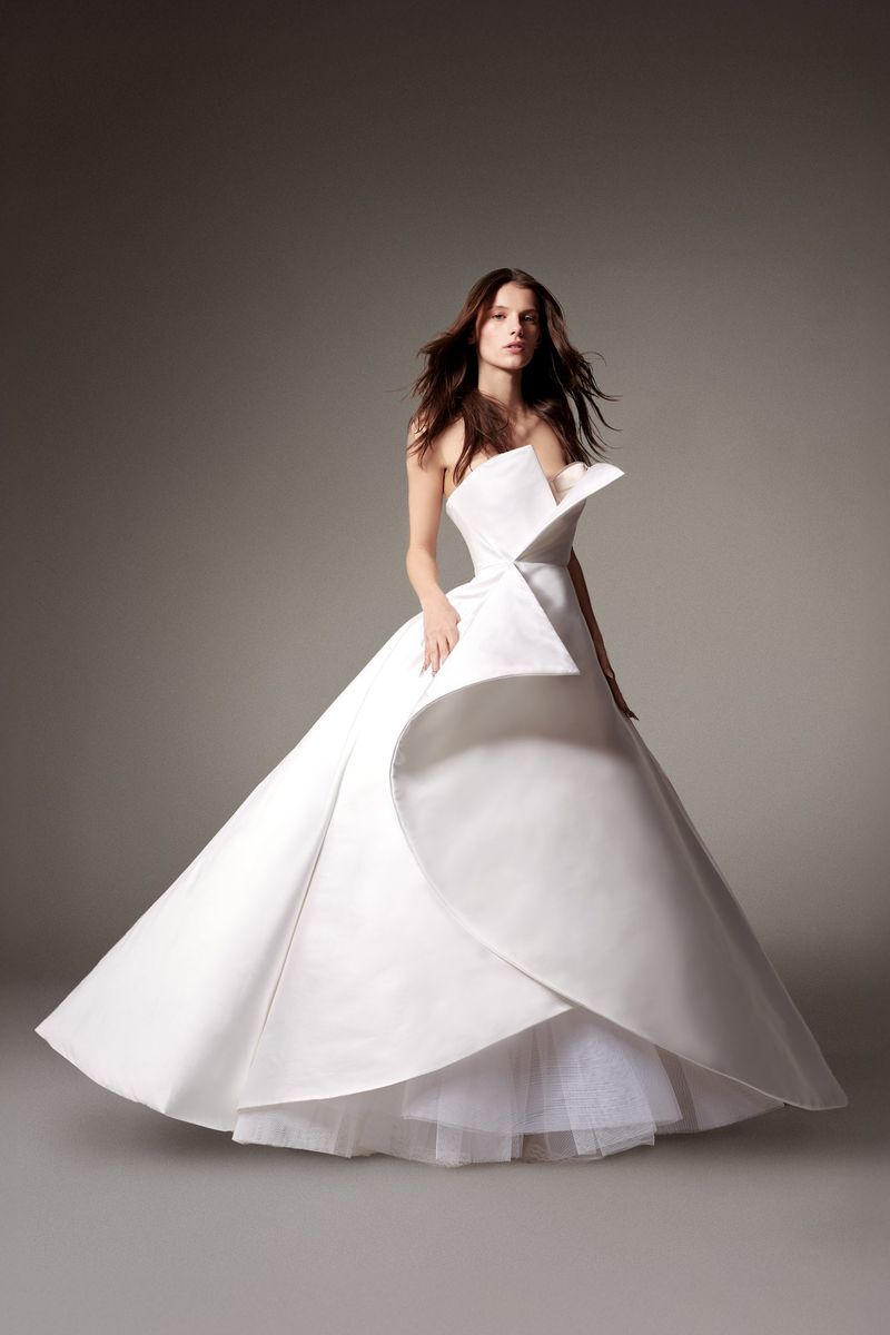 Elegant adult woman in a white strapless gown in a studio setting with soft lighting; showcasing couture fashion.