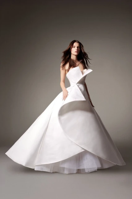 Elegant adult woman in a white strapless gown in a studio setting with soft lighting; showcasing couture fashion.