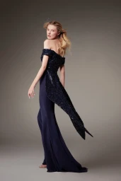 Model in off-the-shoulder dark navy sequined evening gown looking back against a neutral grey studio background