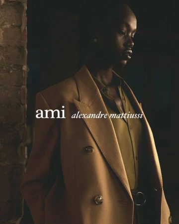 A striking fashion shot of an African woman in a tan blazer and olive shirt, showcasing a blend of urban style and classic elegance.