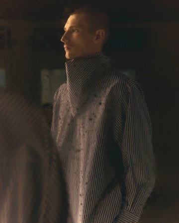 Close-up portrait of a male model wearing a high-collared striped shirt in warm low-key lighting for AMI.