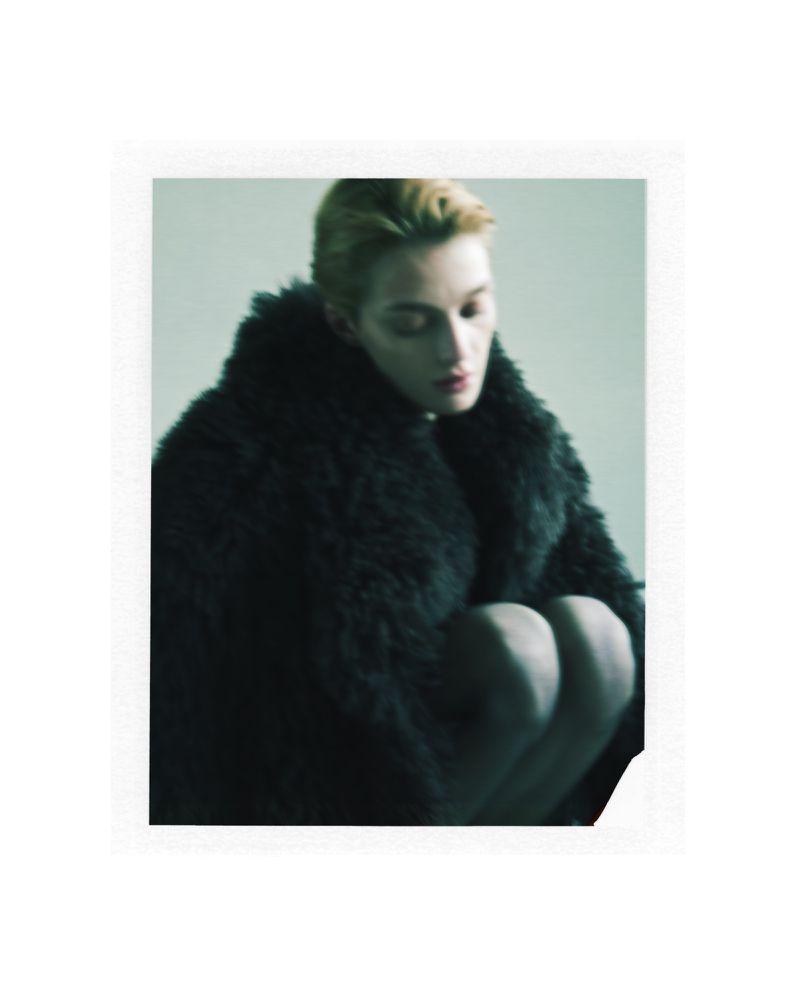 Model wearing a dark fluffy faux fur coat posing against a plain grey studio backdrop for Shoreditch Ski Club AW24.