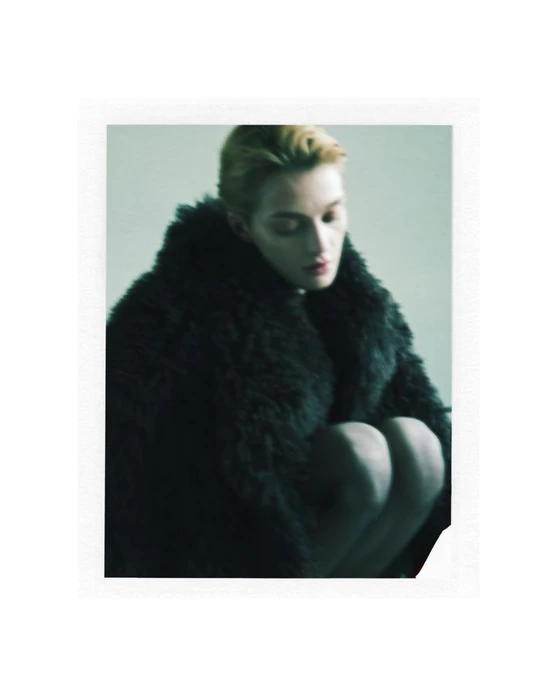 Model wearing a dark fluffy faux fur coat posing against a plain grey studio backdrop for Shoreditch Ski Club AW24.