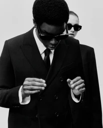 Monochrome fashion portrait of a man and woman in black suits and sunglasses for Ami SS24 eyewear campaign.