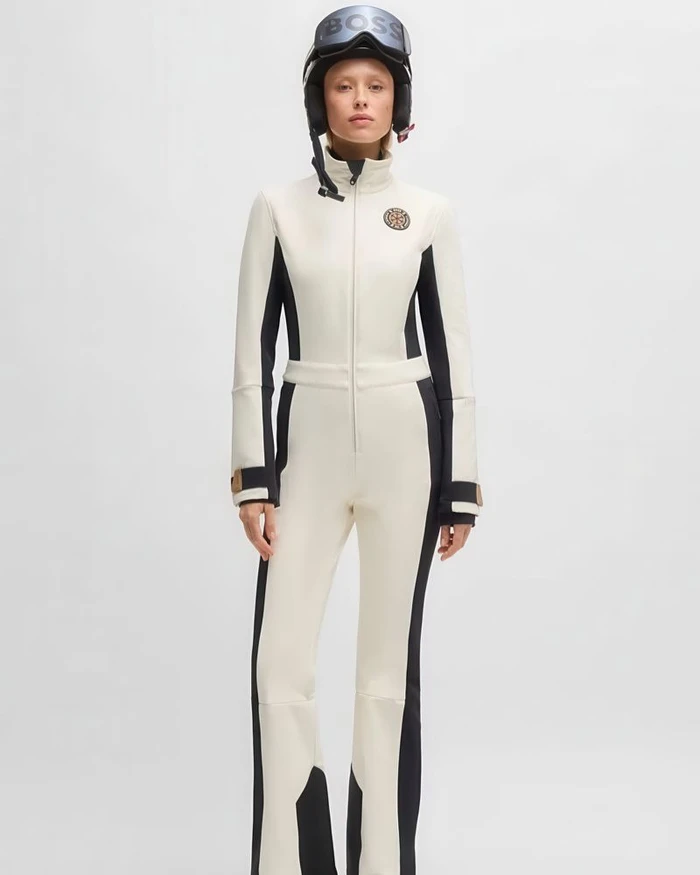Model wearing a white and black ski suit and helmet against a plain white background for BOSS SS25 Ski Collection Campaign