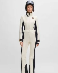 Model wearing a white and black ski suit and helmet against a plain white background for BOSS SS25 Ski Collection Campaign