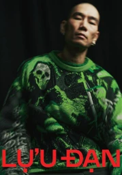 Man wearing a vibrant green patterned sweater featuring skull graphics against a dark background for Lu'u Dan F/W 25 lookbook