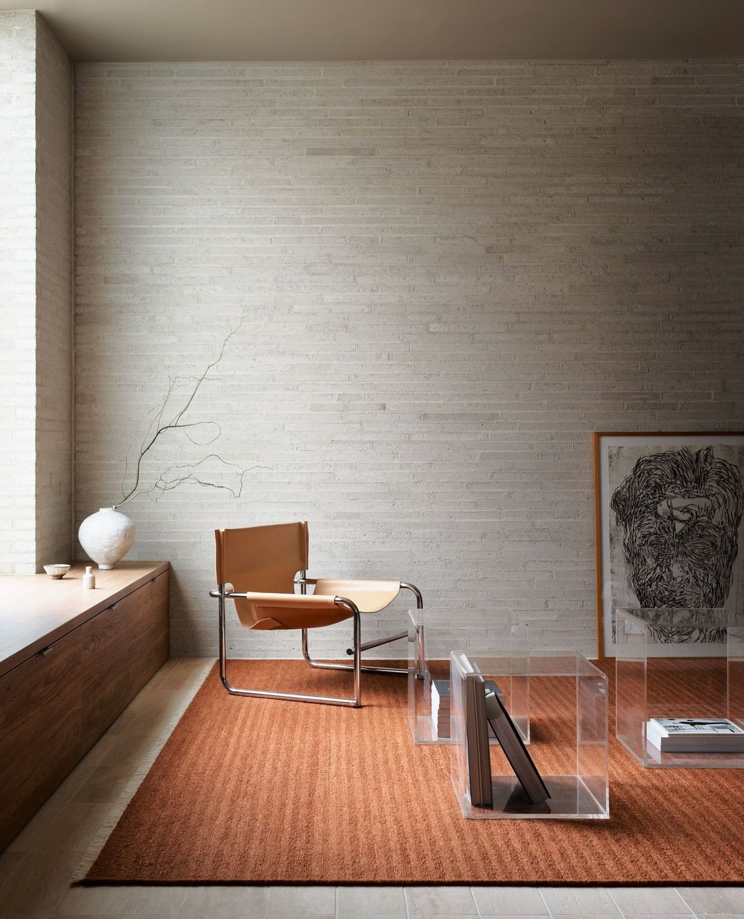 Minimalist interior showcasing a modern chair on a textured rug, complemented by translucent display cases, set against a textured wall.