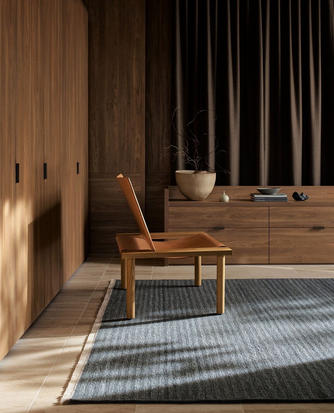 Interior design features a wooden chair on a striped rug, complemented by wooden cabinets, minimalist decor, and neutral color palette.