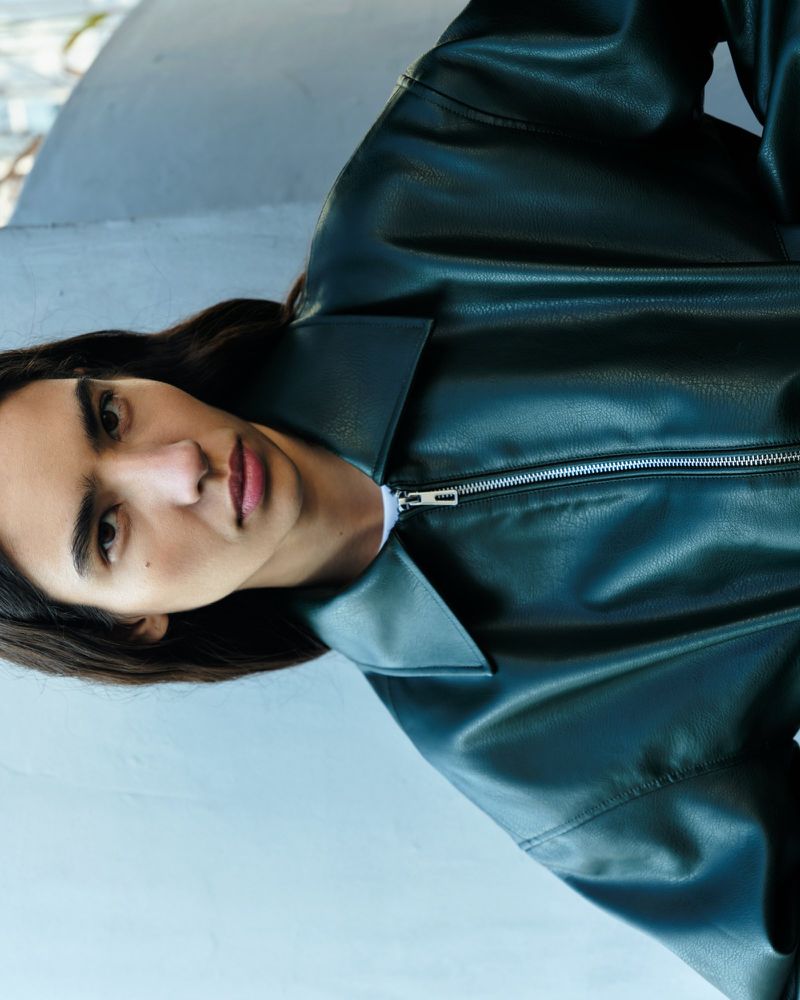 Model wearing a dark green faux leather jacket with a silver zipper in an editorial portrait for EDITED.de.