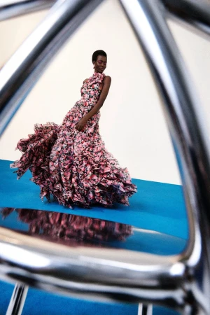 Model in a floral ruffle gown framed by metallic structure in Carolina Herrera Pre-Fall 2025 editorial