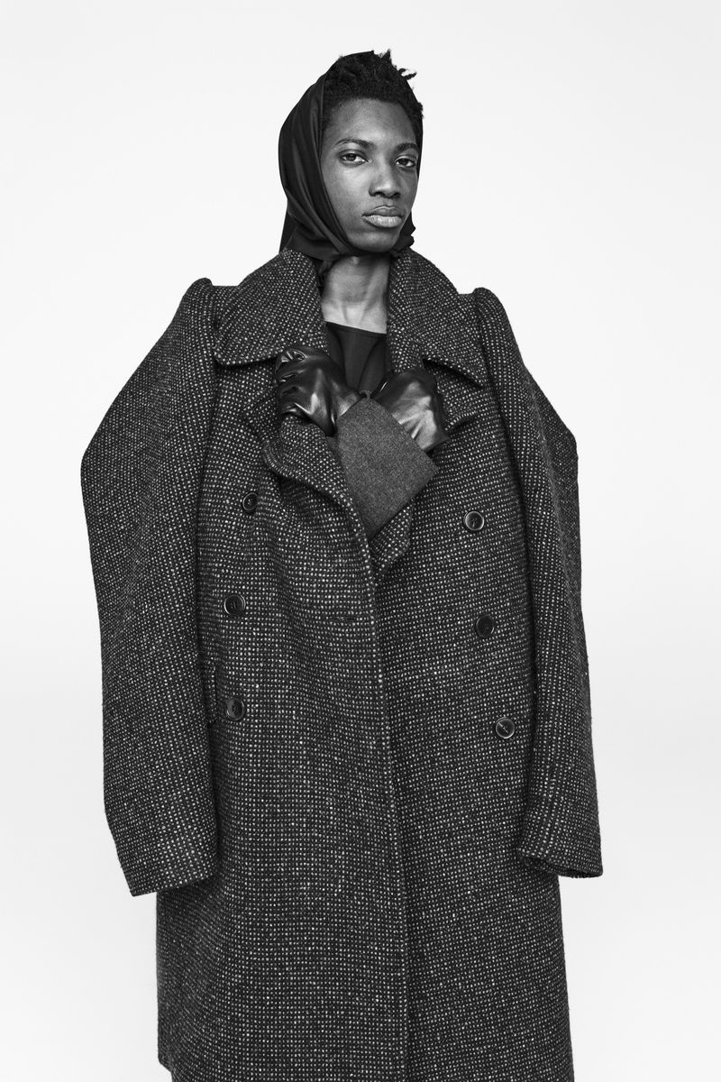 Model in textured grey double-breasted coat wearing a headscarf against a plain white background